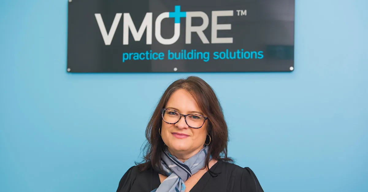 Deana Scott standing in front of the VMORE practice building solutions sign